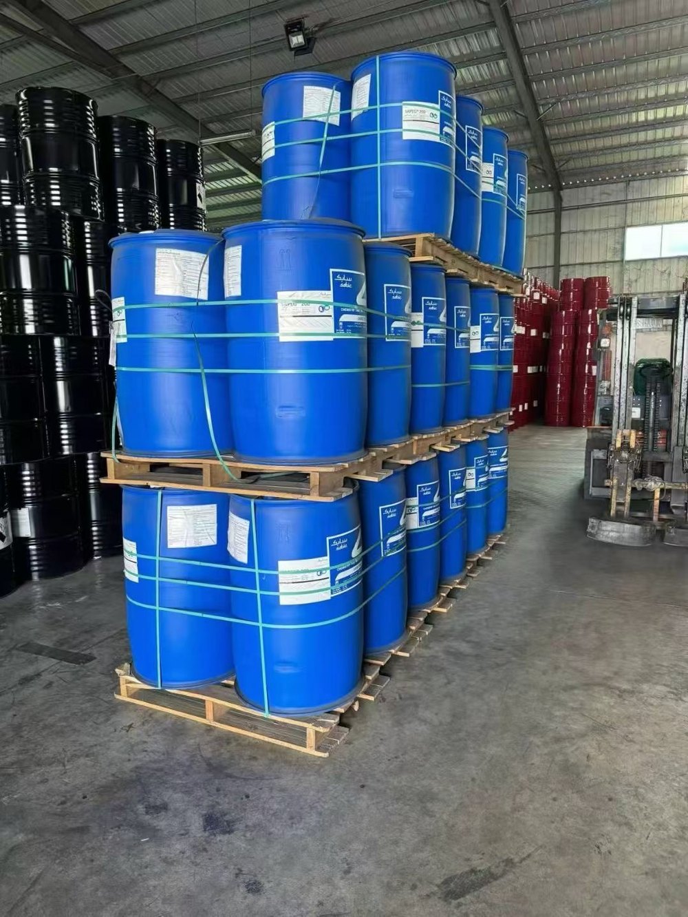 Palletised blue chemical drums strapped and stacked in the MAD Group warehouse